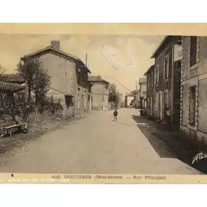 Carte postale ancienne  montrant la rue principale , on appercoit une borne Michelin à la croisée des rues